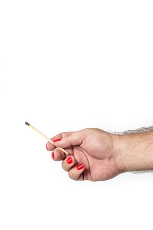 Male hand with red painted fingernails holding burnt out matchstick, isolated on white background. Concept of difference and LGBTの写真素材