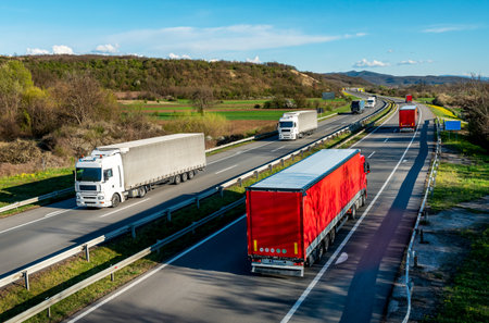 Heavy Highway transportation scene with Convoys or fleets of transportation trucks in both ways,on rural highway under a beautiful blue skyの写真素材