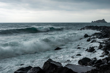 Waves hitting the shore on a cloudy overcast rainy stormy day. Cyclops Coast, black volcanic rocks...