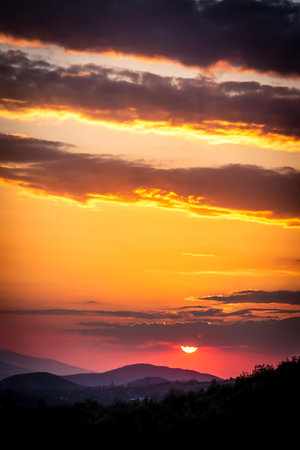Sunset with a mountain view and dramatic sky and cloudsの写真素材