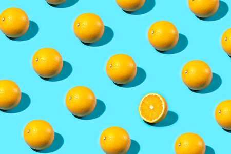 Trendy Summer food pattern made with oranges and one sliced orange on bright light blue background....
