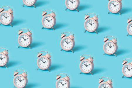 Trendy pattern made with pink alarm clocks on bright blue backgroundの写真素材