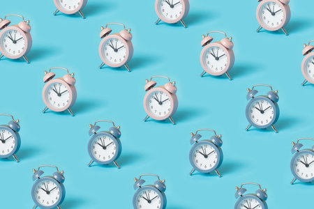 Trendy pattern made with pink and blue alarm clocks on bright blue backgroundの写真素材