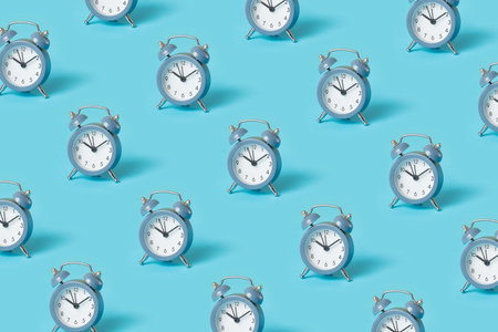 Trendy pattern made with blue alarm clocks on bright blue backgroundの写真素材