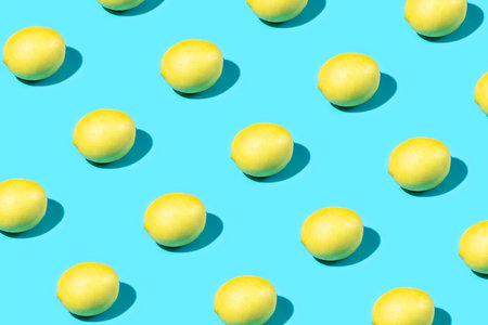 Trendy Summer food pattern made with yellow lemon on bright light blue background. Minimal summer concept.の写真素材