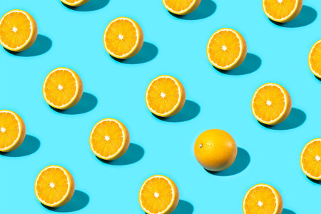 Trendy Summer food pattern made with orange slice with one whole orange on bright light blue background. Minimal summer concept.の写真素材