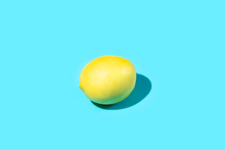 Single Ripe Juicy Whole Lemon on Blue Background. Vitamins Healthy Diet Summer Superfoods Concept. Food Poster Banner Template. Copy Spaceの写真素材