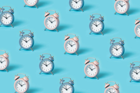 Trendy pattern made with pink and blue alarm clocks on bright blue backgroundの写真素材