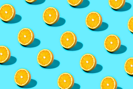 Trendy Summer food pattern made with orange slice on bright light blue background. Minimal summer concept.の写真素材