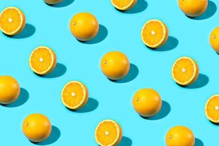 Trendy Summer food pattern made with oranges on bright light blue background. Whole and sliced oranges. Minimal summer concept.の写真素材