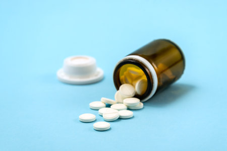 White medical pills and tablets spilling out of a drug bottle. Macro top down view with copy space.の写真素材