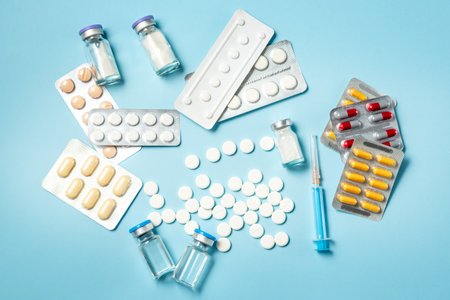 Medicine on the table. Colorful pills, capsule, ampullae and syringe on a blue backgroundの写真素材