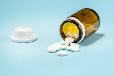 White medical pills and tablets spilling out of a drug bottle. Macro top down view with copy space.の写真素材