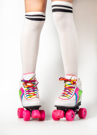 Portrait of woman legs wearing four-wheeled roller blades with colorfull laces on white backgroundの写真素材