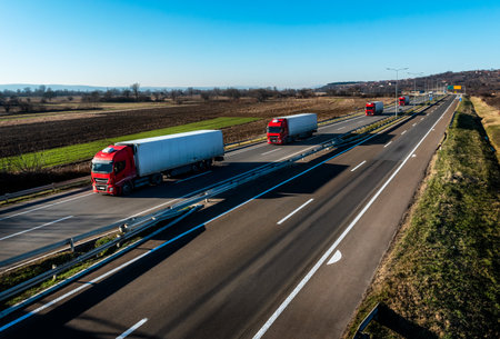 Convoy of red Trucks with white containers on highway, cargo transportation concept in springtime - freight serviceの写真素材