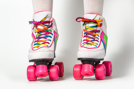 Portrait of woman legs wearing four-wheeled roller blades with colorfull laces on white backgroundの写真素材