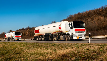 Gasoline tankers, Oil trailers, Tank trucks on highway close up on a Highway road with a beautiful sky in the backgroundの写真素材