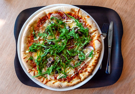 Pizza Margherita with Fresh Arugula Leaves served in a plate on Wooden tableの写真素材