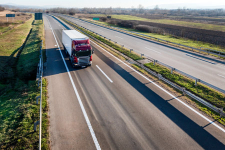 Large Red Transportation Truck with white trailer on a highway road through the countryside in a...