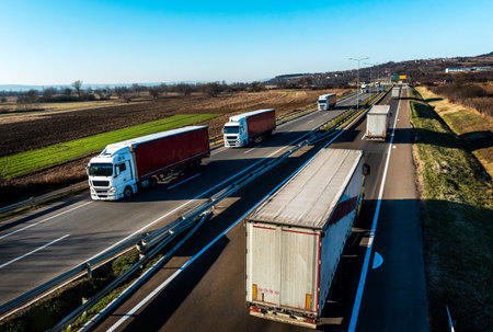 Highway transport. Transportation Trucks in lines passing both ways on a rural countryside highway under a beautiful blue skyの写真素材