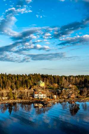 Small idyllic port in the Swedish archipelago outside of Stockholm with beautiful reflection lighted with sunspot at autumn evening.の写真素材