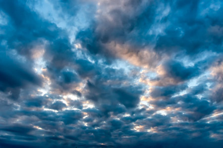 Majestic colorful cloudscape with dark blue clouds and pastel tones of piercing sun raysの写真素材