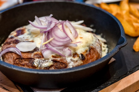Onion Burger. Meat burger of ground meat fried in oil on a frying pan with three types of onions, close upの写真素材