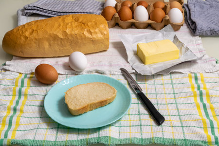 Breakfast with boiled eggs and butter, a slice of bread on a blue plateの写真素材
