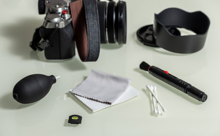 Tools for cleaning camera with mirrorless camera and lens, flash. Different objects on white glass...