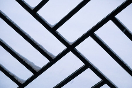 Snow on the frosty metal fence in winter landscape. Abstract background