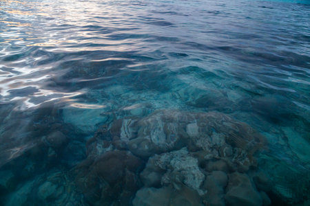 Blue sea water with ripples and a stone in the foreground.の写真素材