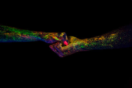 concept of connecting hands creative shooting in neon light male and female palms together glow in the dark under the ultravioletの写真素材