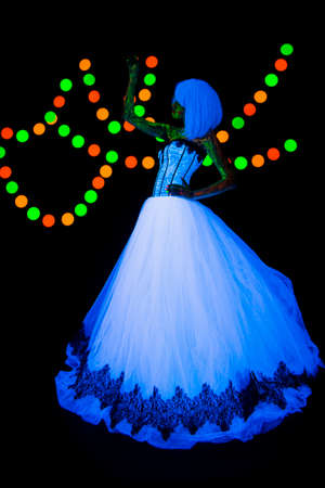 Wedding photo session of the bride Neon photography bright colorful on a dark background in ultraviolet rays young girl in white wedding dress posing in vogue styleの写真素材