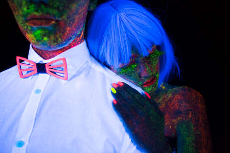 Neon photography in the rays of the ultraviolet couple in love guy and girl bride on his shoulder with the groom at the wedding UV radiation lovestoryの写真素材