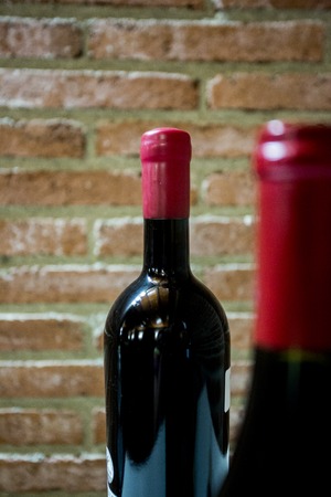 Bottles of red wine on a brick wall backgroundの写真素材
