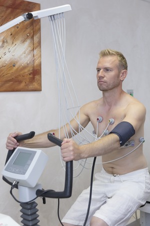 doctor with electrocardiogram equipment making cardiogram under load test to male patient in hospital clinicの写真素材