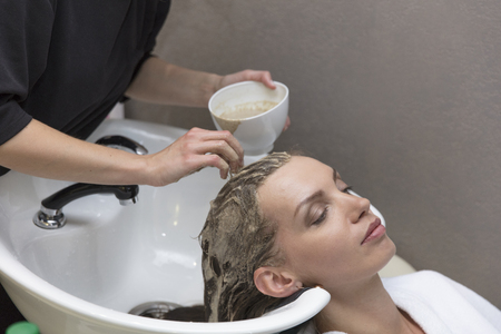 Hair beauty care, moisturizer application, hairdresser, hair mask of a beautiful girl, natural, health and beauty, closeup in beauty salonの写真素材