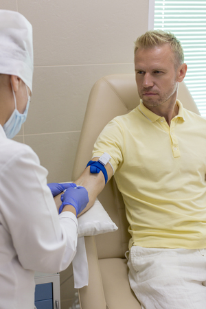 Blood donor at donation, transfusion. Close up right arm of a business man receiving blood in hospital. Healthcare and charity. Also concept image background for World blood donor day - June 14 .の写真素材