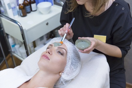 Young beautiful girl in mask for face folting in beauty spa salon.の写真素材
