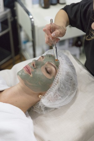 Young beautiful girl in green mask for face relaxing in spa salon.の写真素材