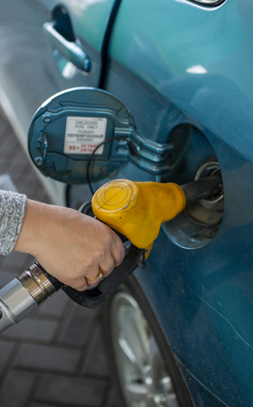 Hand refueling the fuel tank of the machine with diesel or gasoline at a filling stationの写真素材