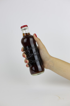 Atlanta, Georgia, USA - July 22, 2018: woman hand with red nails holding historical glass coca-cola contour classic bottle from USA on white backgroundのeditorial素材
