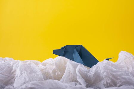 whale on a wave handmade origami craft paper art on a yellow paper backgroundの写真素材