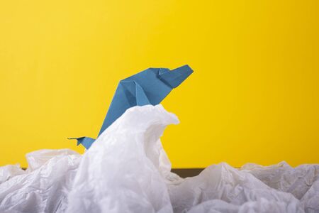 whale on a wave handmade origami craft paper art on a yellow paper background