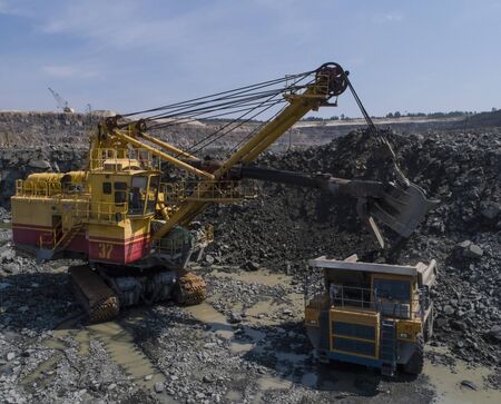 Huge industrial dump truck in a stone quarry loaded transporting marble or granite shot from a drone...
