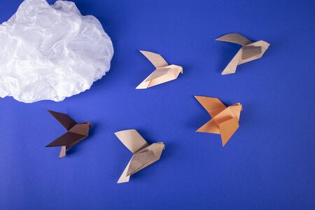 Migration of birds concept of autumn handmade origami birds fly away from the cold on a paper...