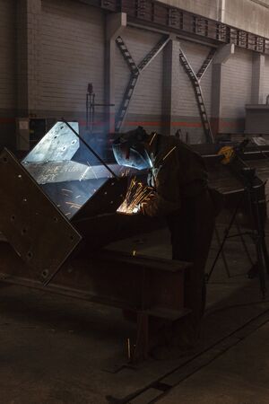 Industrial Worker at the factory welding closeup with metal parts sparks