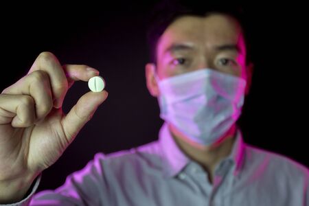 a guy in surgical mask. Focus on pill in hand.の写真素材