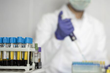 Lab technician assistant analyzes blood test in clinical laboratory adding fluid to test tubes with...