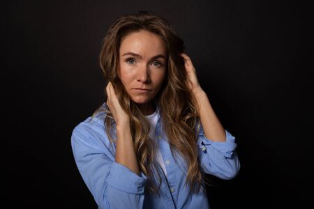 Attractive caucasian woman looking seriously and calmly at camera. Hands in hairの写真素材